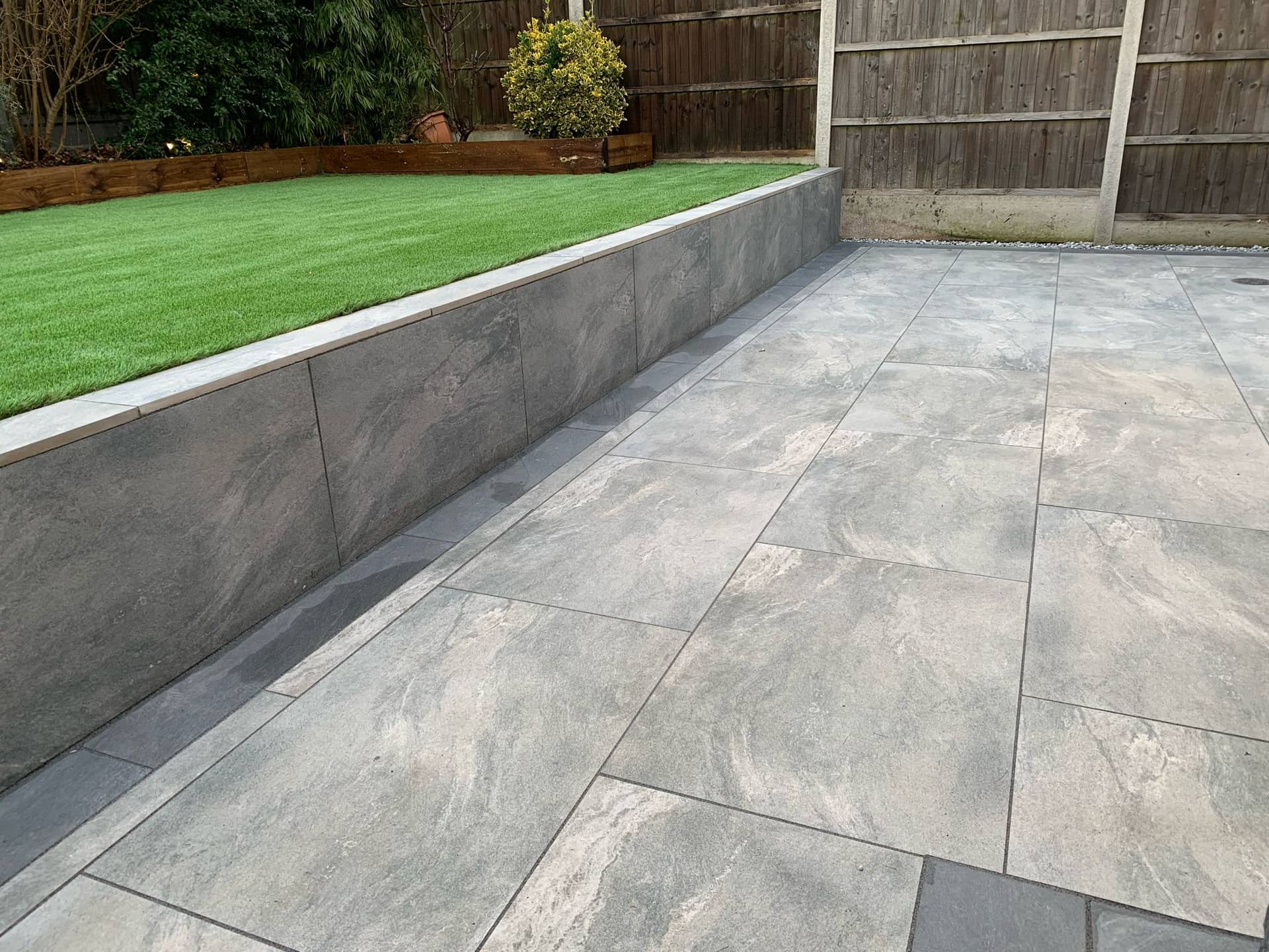 Full view of three-tiered garden in Billericay showing porcelain paving, artificial grass and sleeper beds