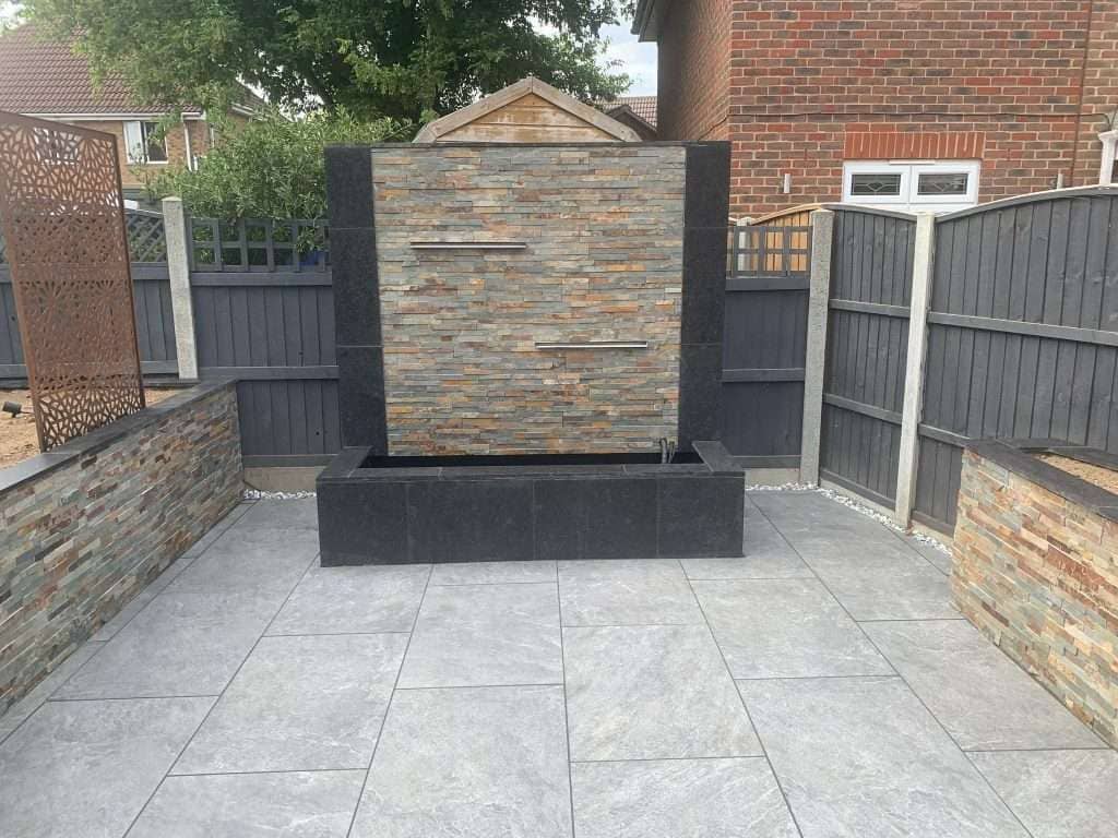 Close-up of bespoke stone clad water feature with cascading blade in Billericay garden