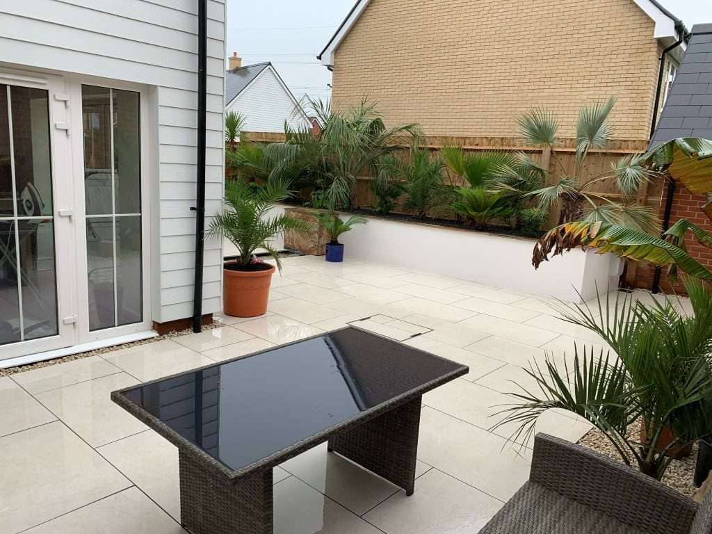 Cream porcelain patio with outdoor dining table and seating in Rayleigh garden