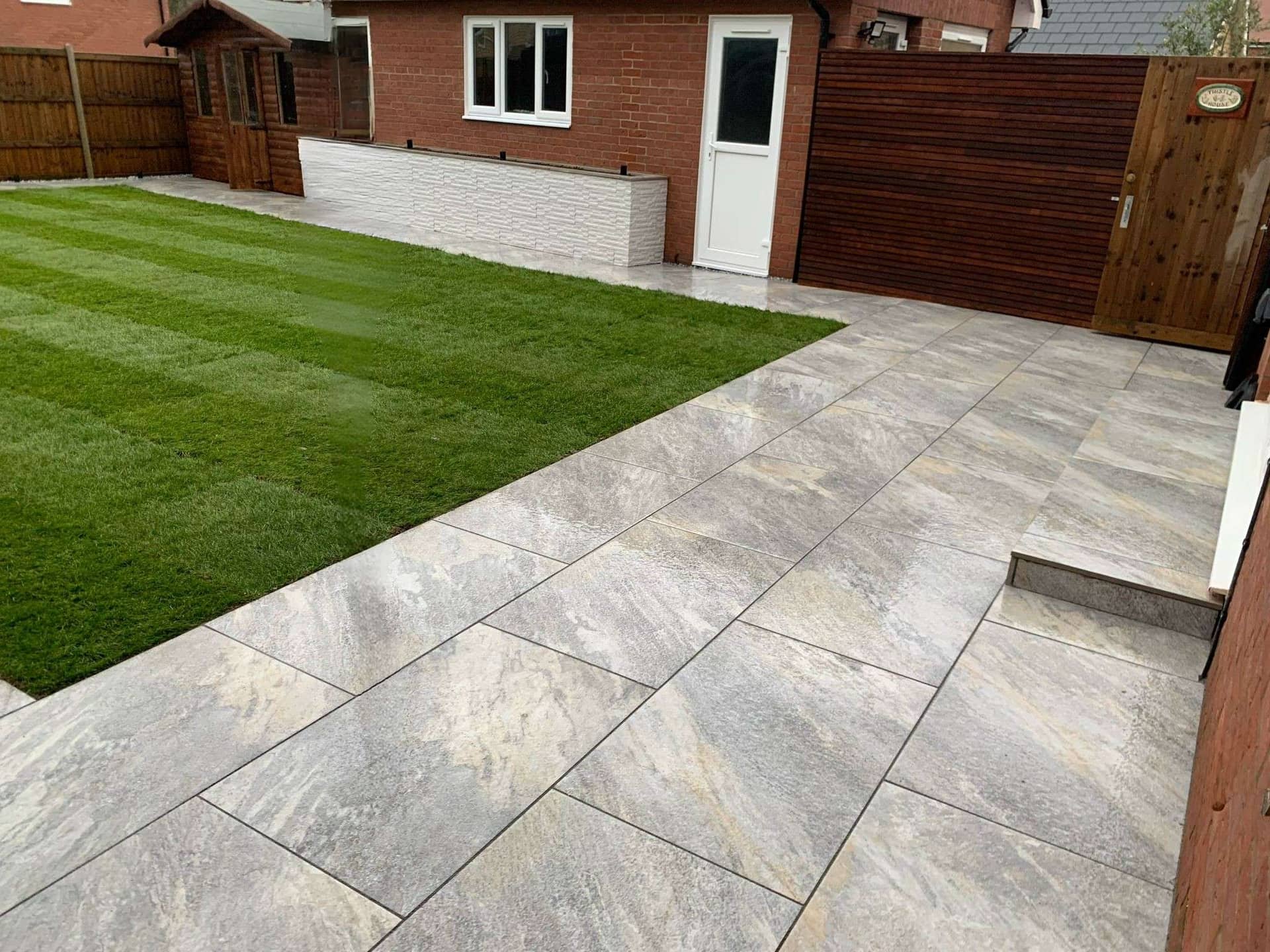 Modern stone porcelain patio with striped lawn and raised planter wall in Billericay garden makeover