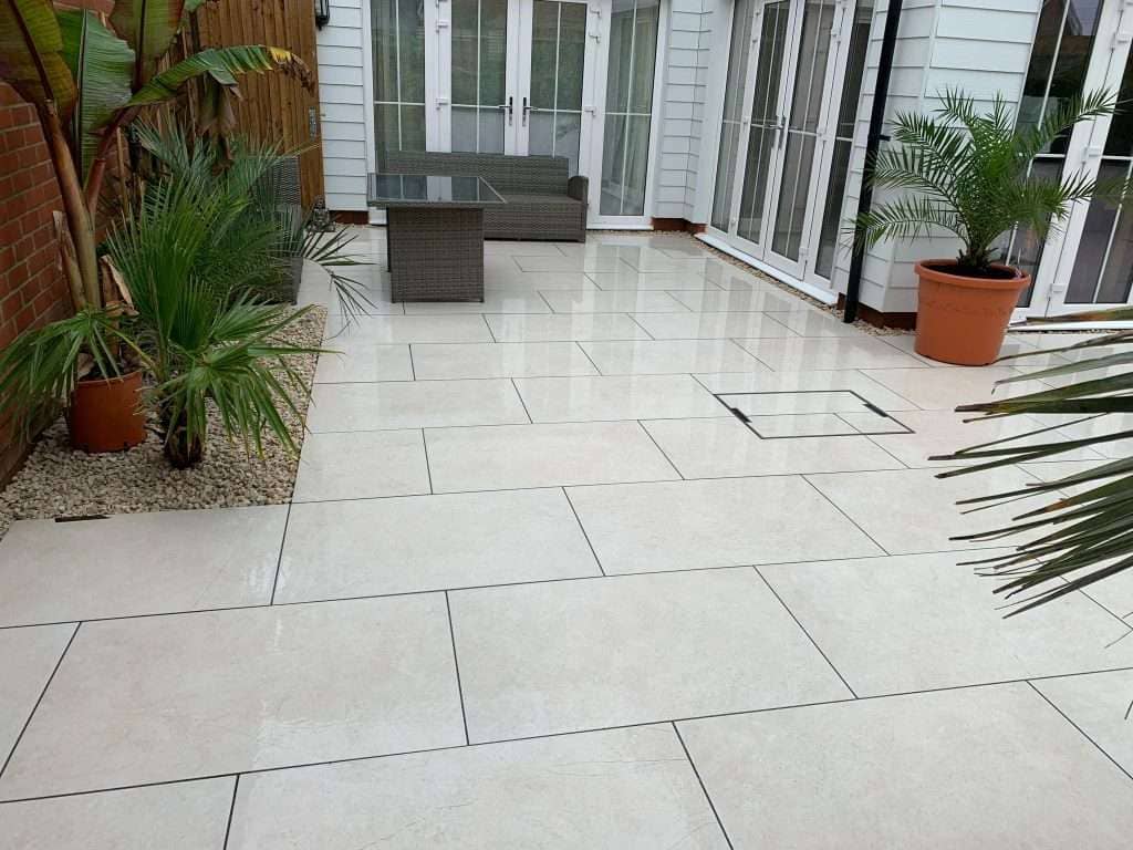 Outdoor wicker lounge seating on cream porcelain patio with tropical palm planting