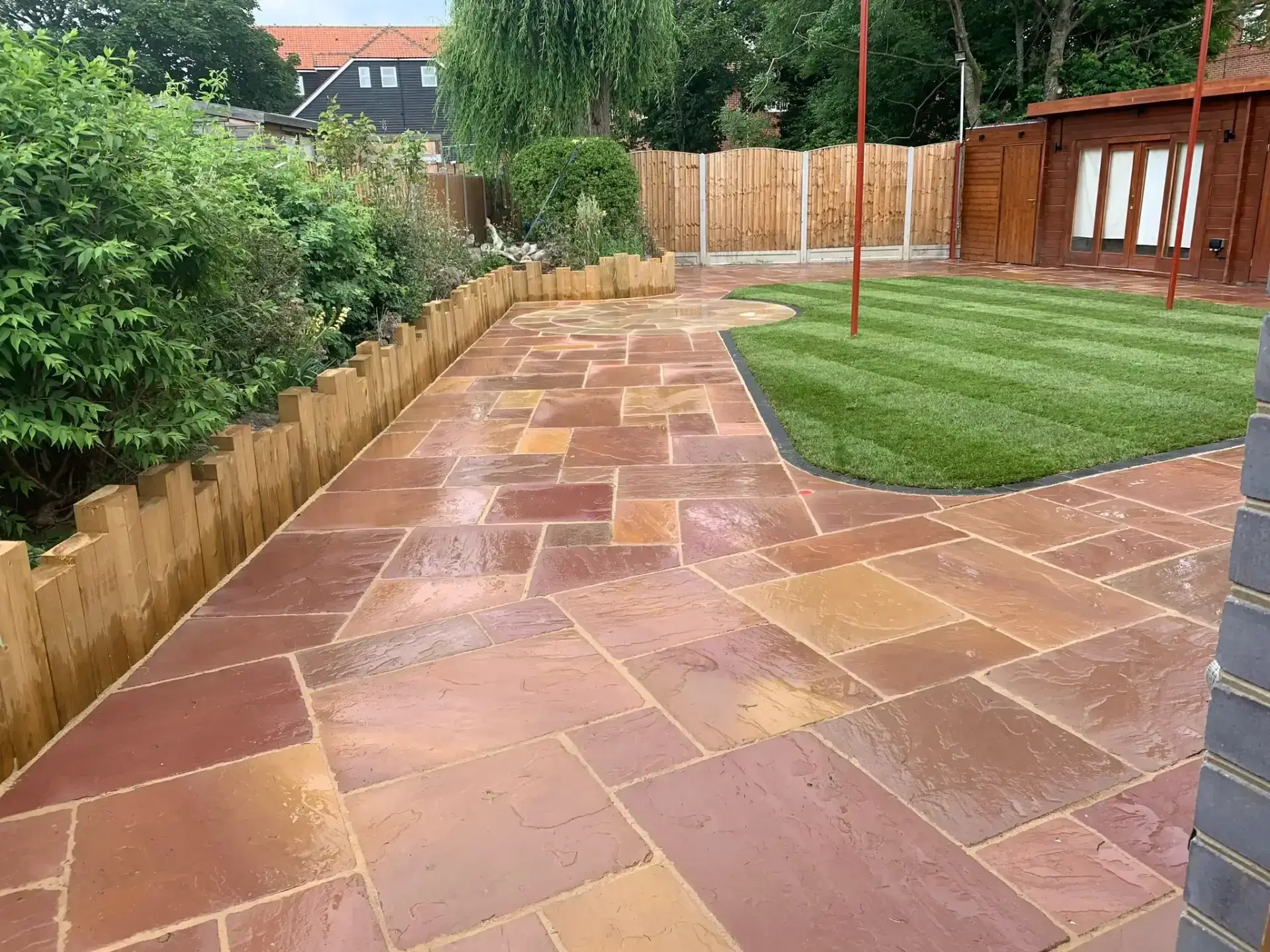 Indian sandstone patio with curved lawn edging in Wickford