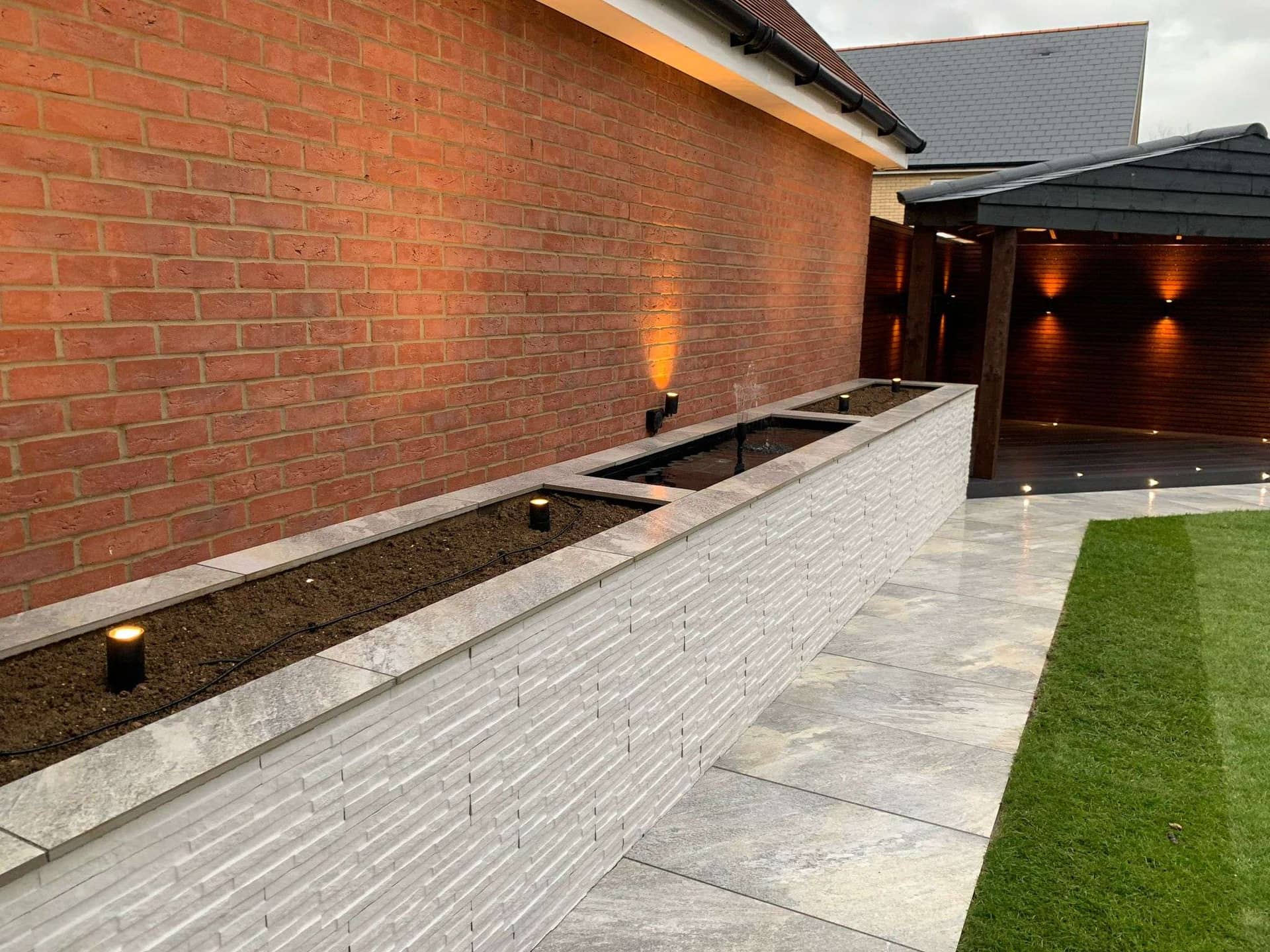 Stone-tiled raised planter wall with integrated warm LED garden lighting