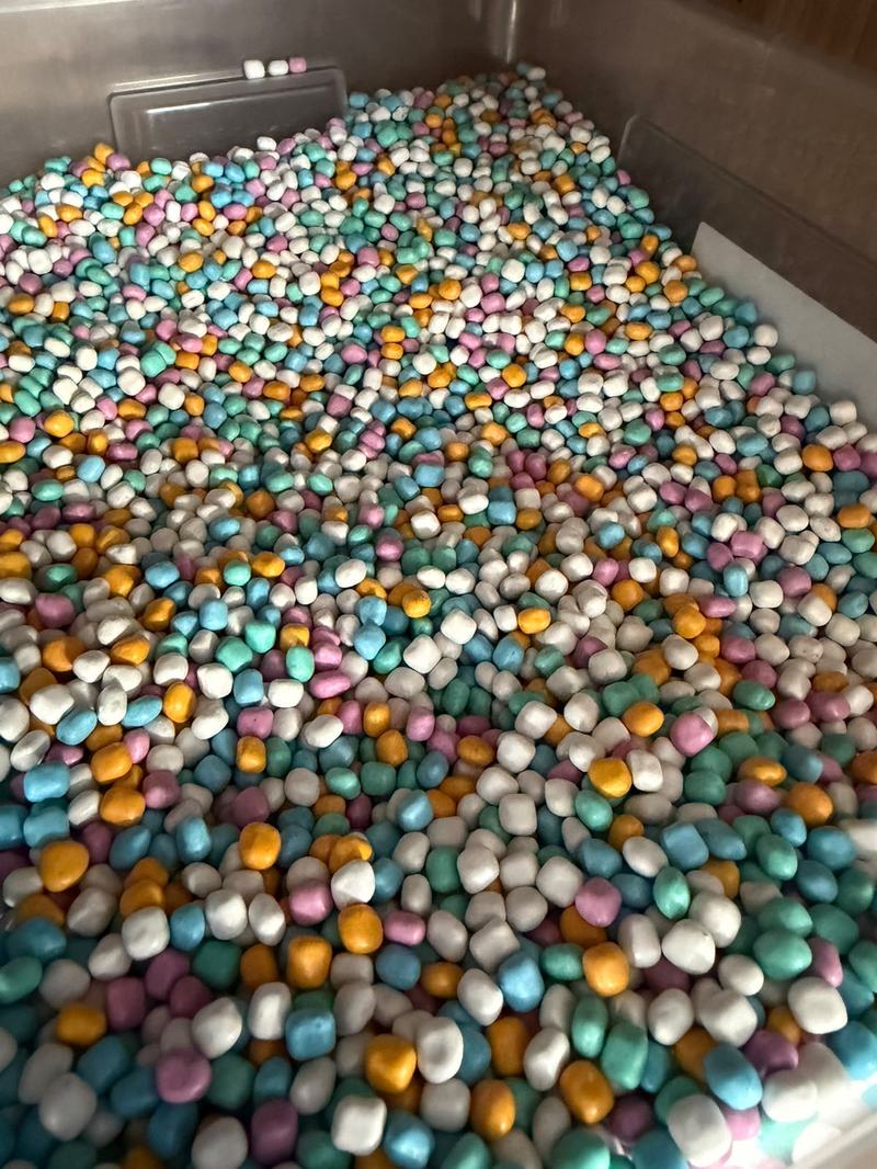 Kiste mit bunten, matten Kügelchen in Türkis, Gelb, Rosa und Weiß