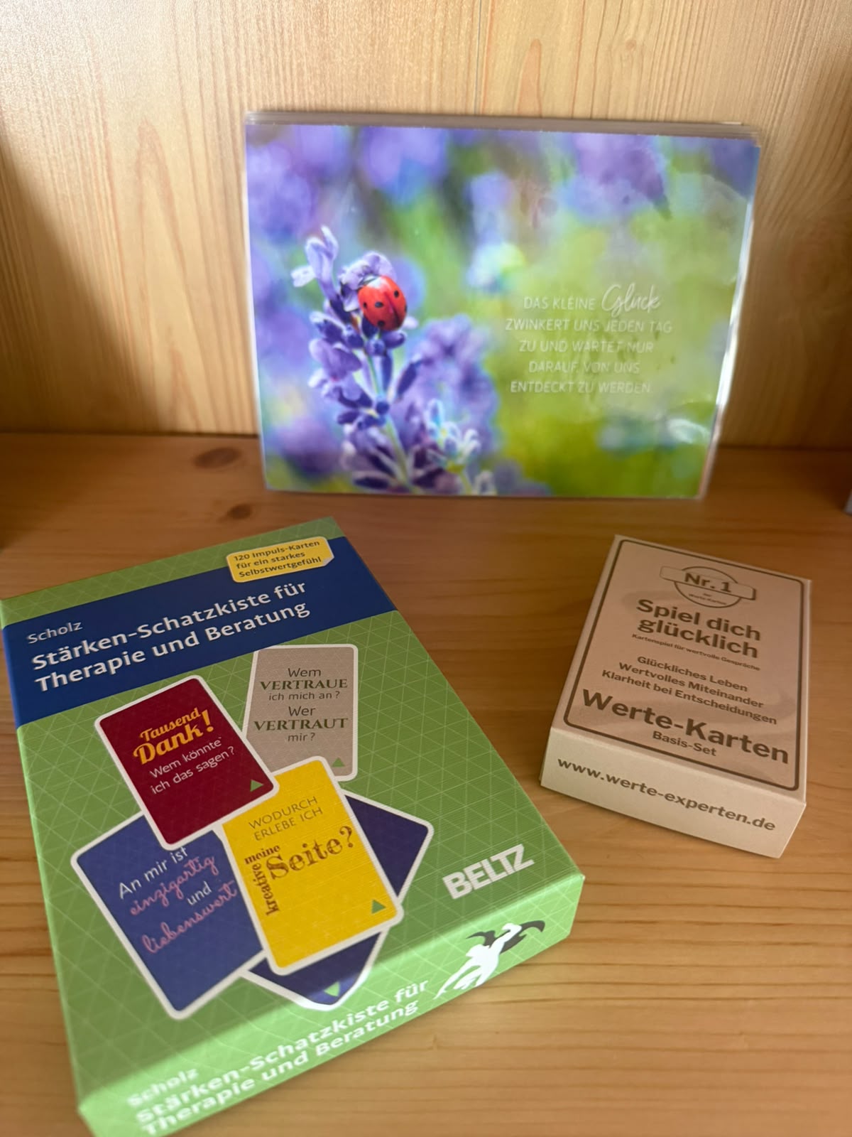 Regal mit Kartensets für Therapie und Beratung und einer Postkarte mit Marienkäfer