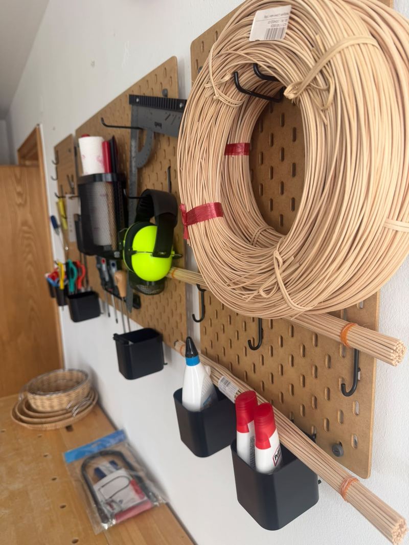 Lochplatten-Wand mit Rattan-Flechtmaterial, Werkzeug, Leim und einem Kapselgehörschutz