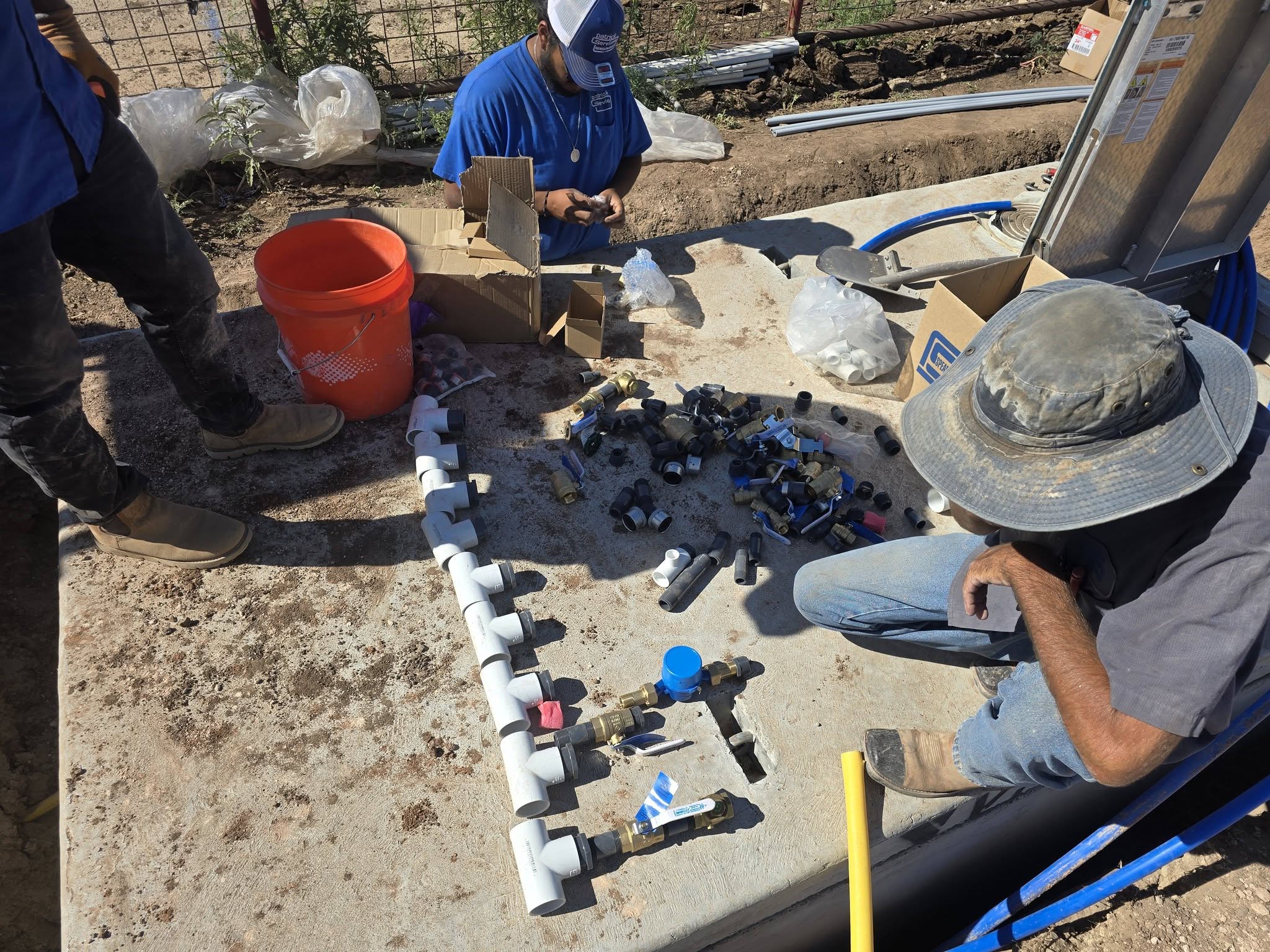 Patrick Plumbing Service technicians laying out pipe fittings and valves for a new water line installation in Amarillo TX