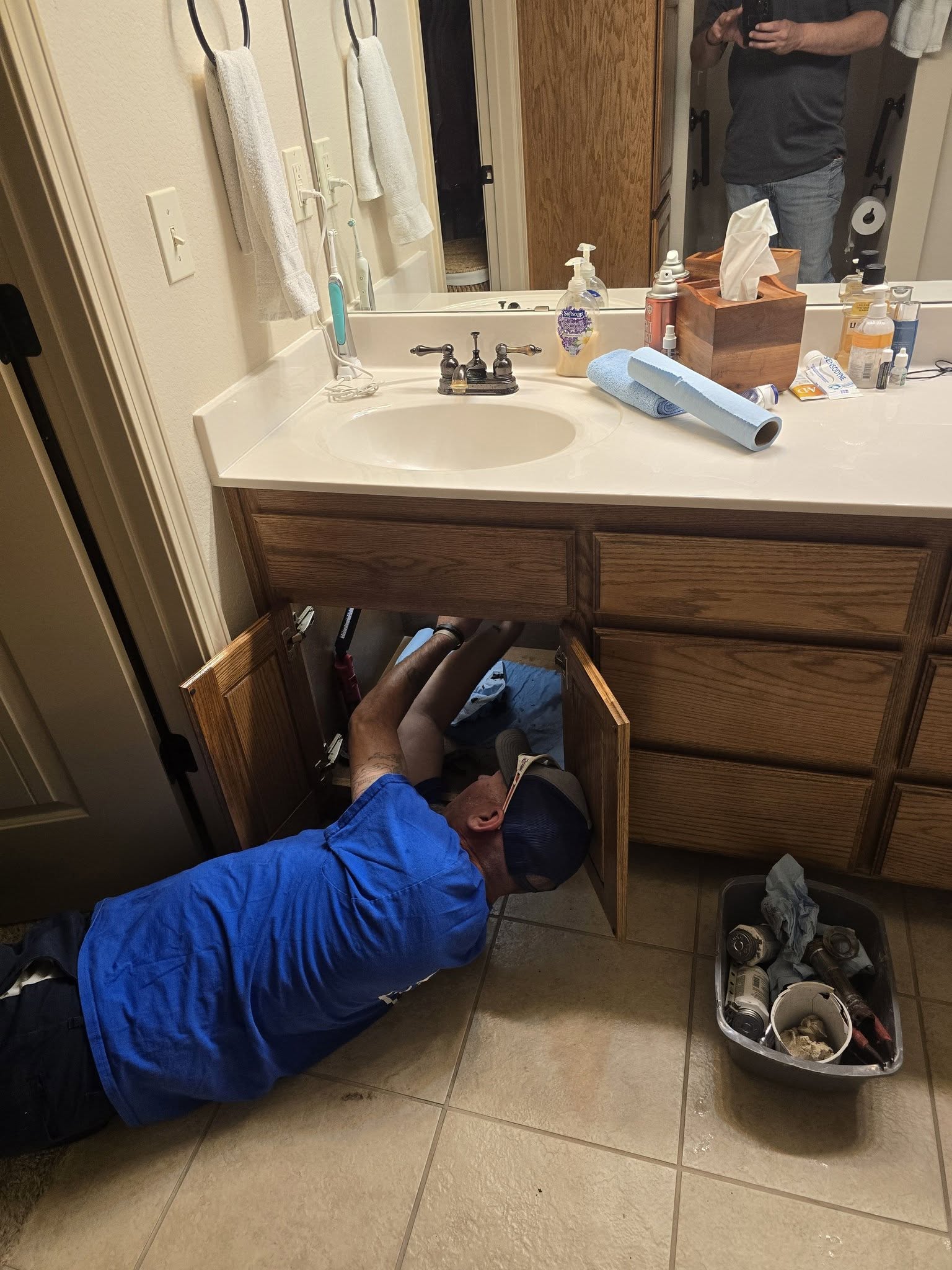Patrick Plumbing Service technician repairing a bathroom sink plumbing under the vanity