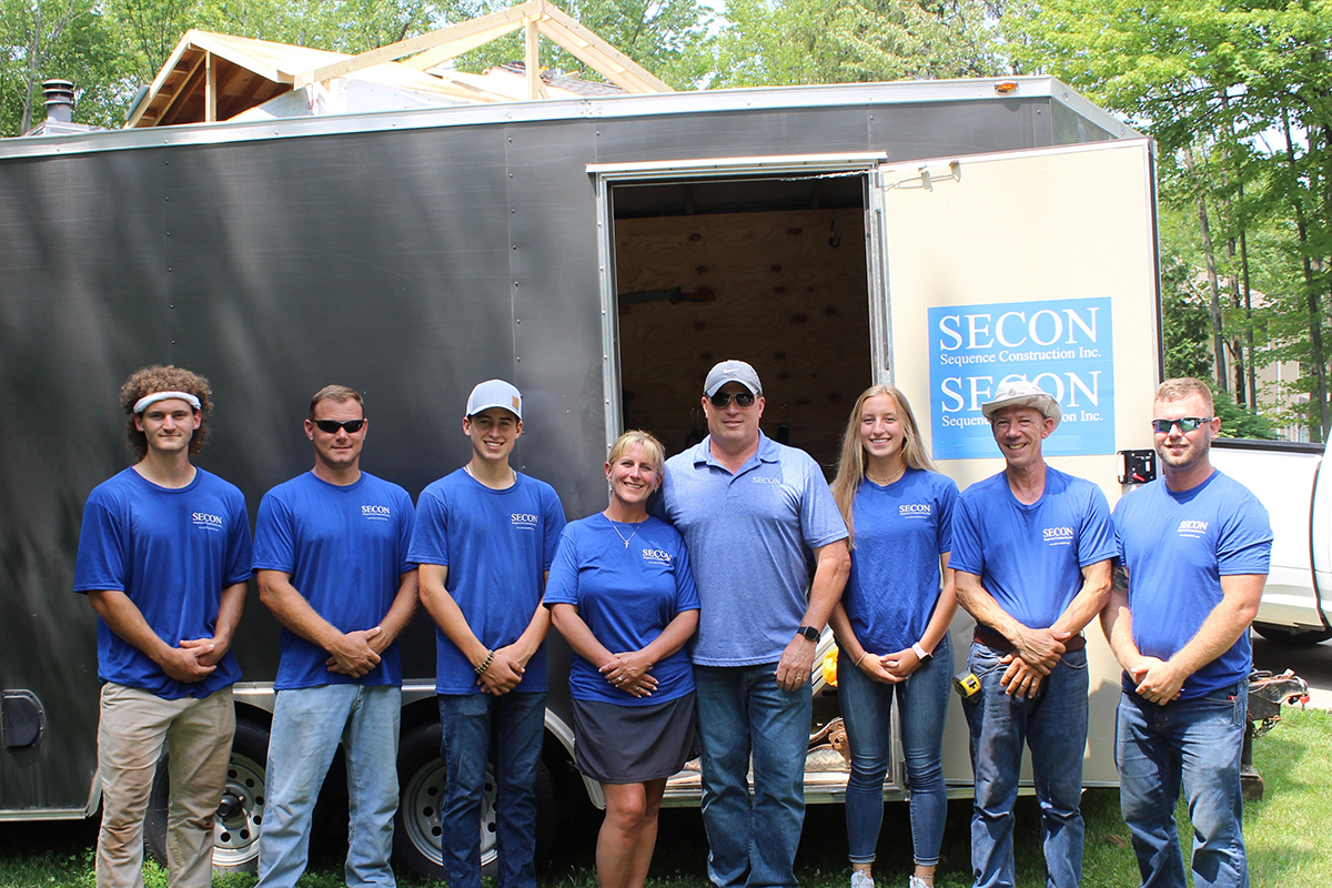 SECON team in matching branded blue company shirts outside job trailer