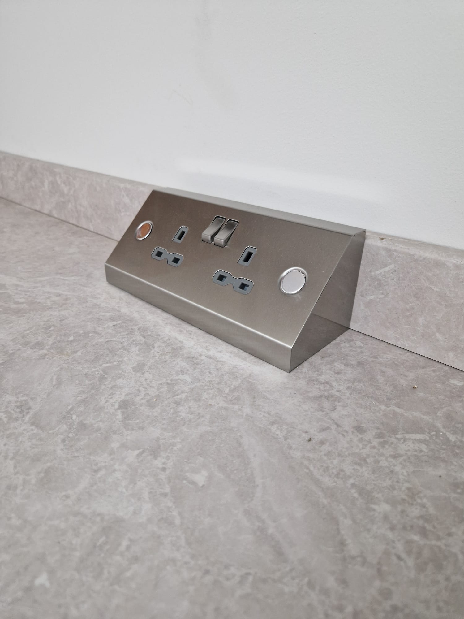 Brushed stainless steel angled countertop power socket pod installed flush against quartz worktop