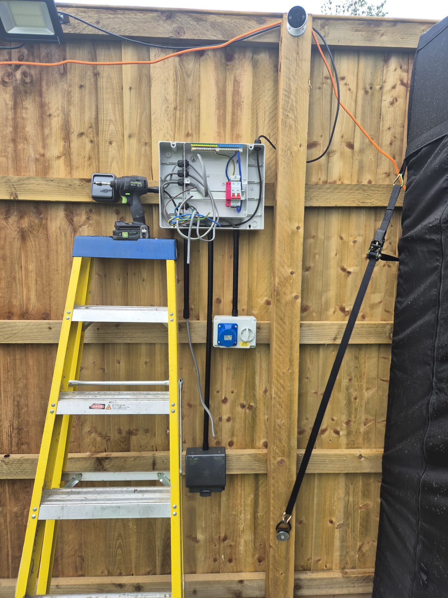 External weatherproof enclosure with circuit isolator, commando socket and power feed mounted to garden timber fence