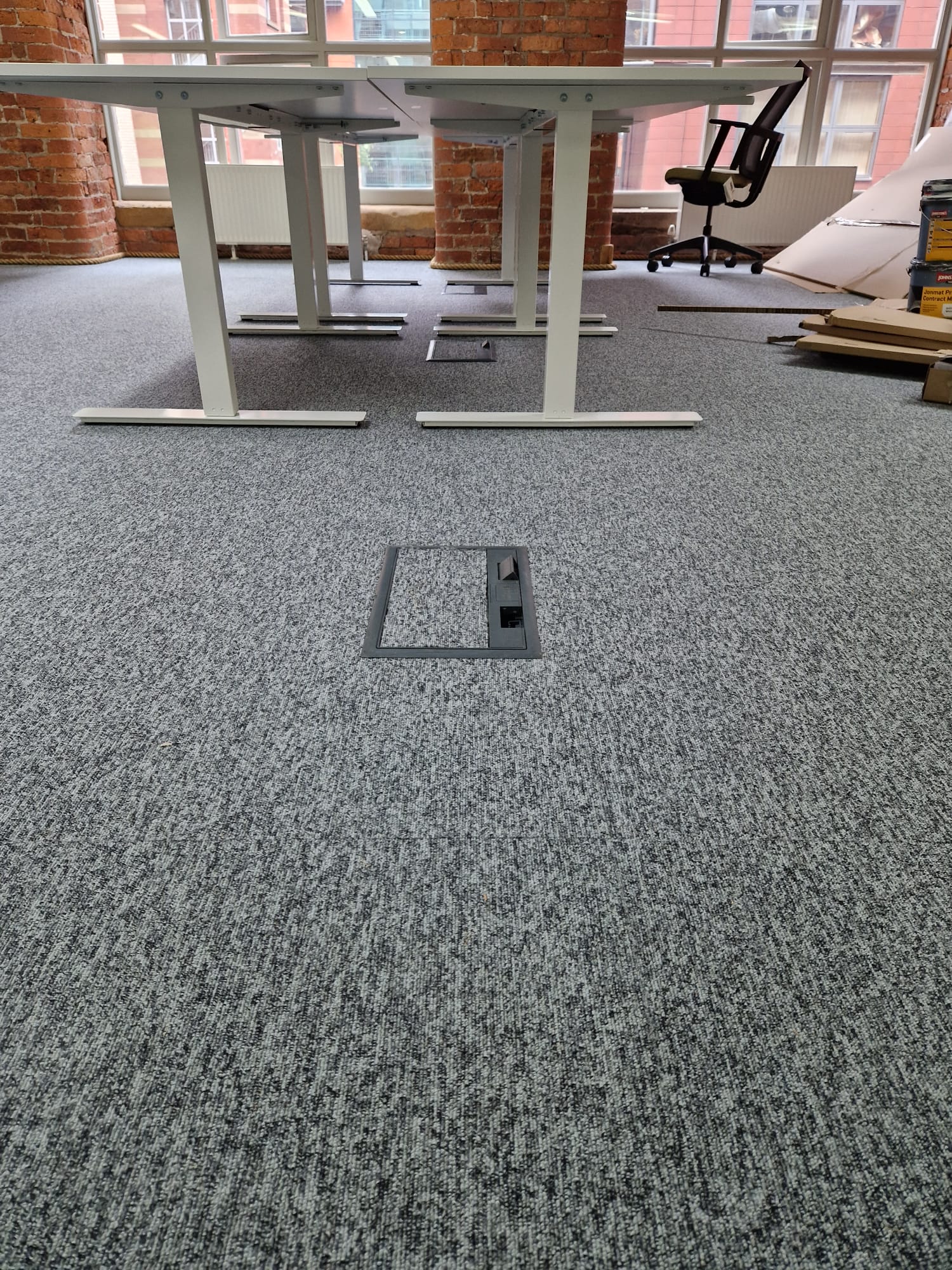 Commercial raised access floor box with flush carpet lid providing power and data sockets under desks