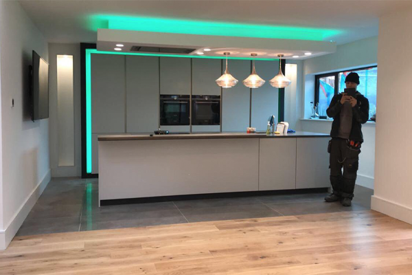 Modern kitchen island with suspended bulkhead, ambient green halo lighting, pendant lights and built-in appliances
