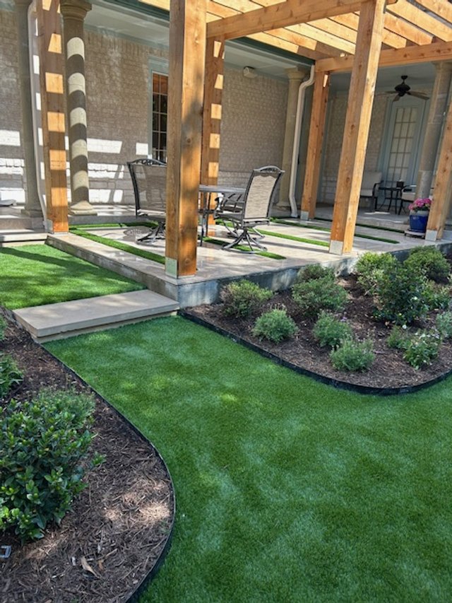 Synthetic turf alongside a covered porch and planting beds