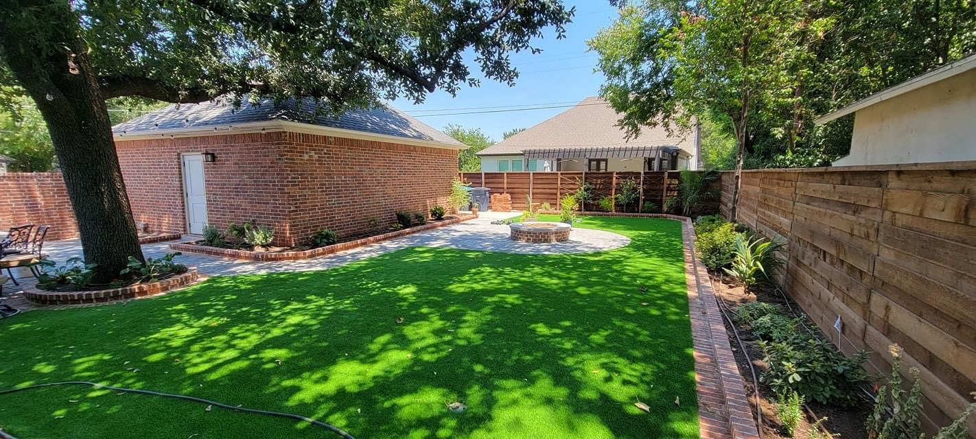 Paved gathering area with a fire pit beside installed turf