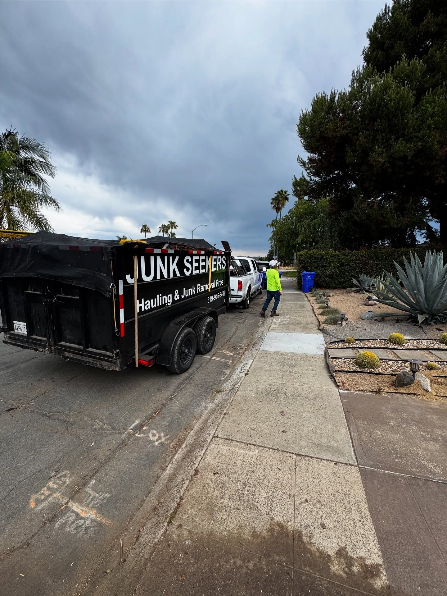 A black construction debris dump trailer parked safely at a residential job site