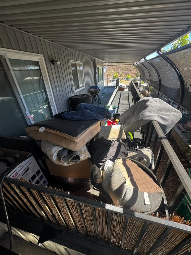 Unwanted items piled on a covered mobile home deck in El Cajon before junk removal.
