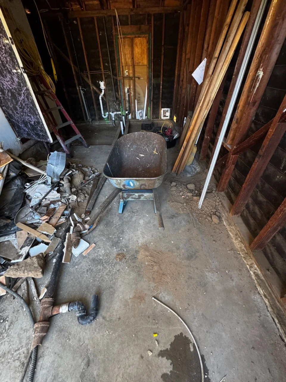 Demolition debris and a wheelbarrow inside a Pacific Beach renovation work area.