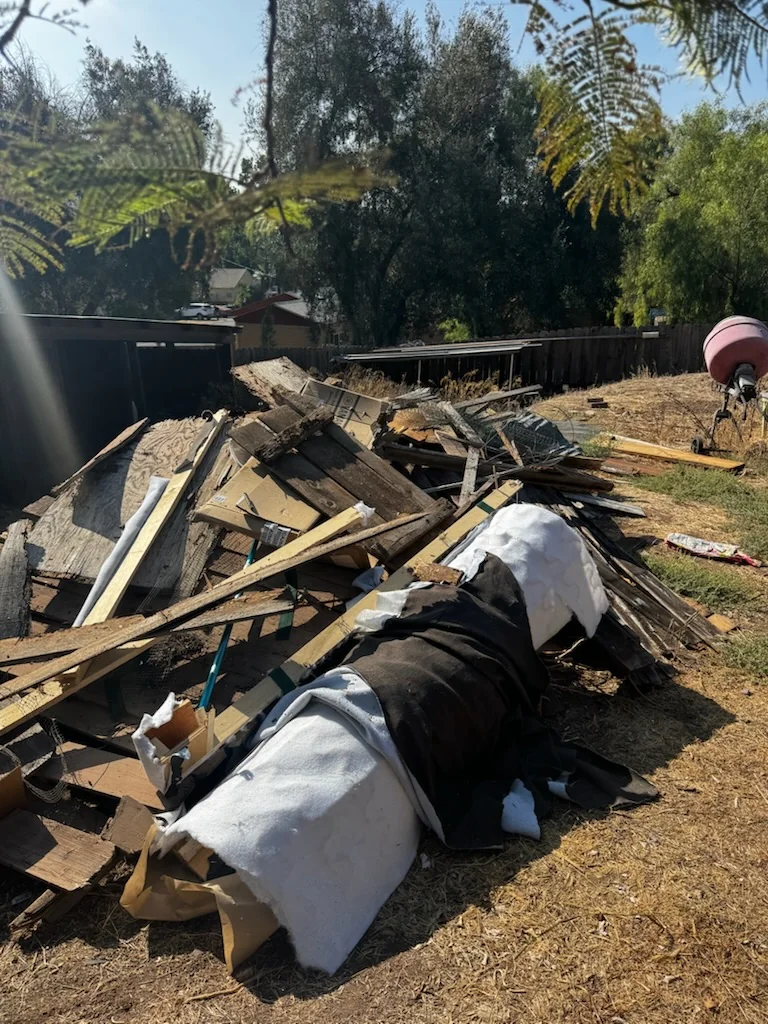 Wood, demolition debris, and mixed trash before cleanup at a Spring Valley property.