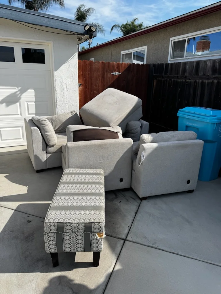 Gray sectional sofa pieces outside beside a garage at the Clairemont Mesa property.
