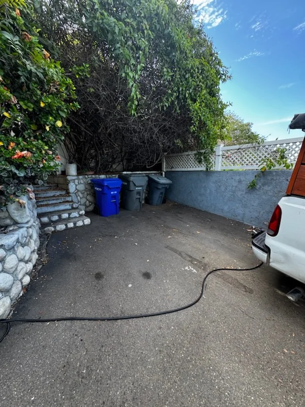 Cleared pickup area beside outdoor bins after trash and cardboard removal in La Mesa.