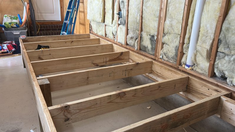 Wood floor joist framing platform under construction with wall insulation
