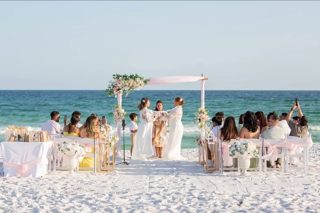 Beach wedding ceremony with floral canopy and seated guests overlooking the ocean in Panama City Beach