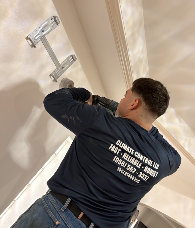 Climate Control LLC technician in company uniform installing HVAC equipment in Laredo