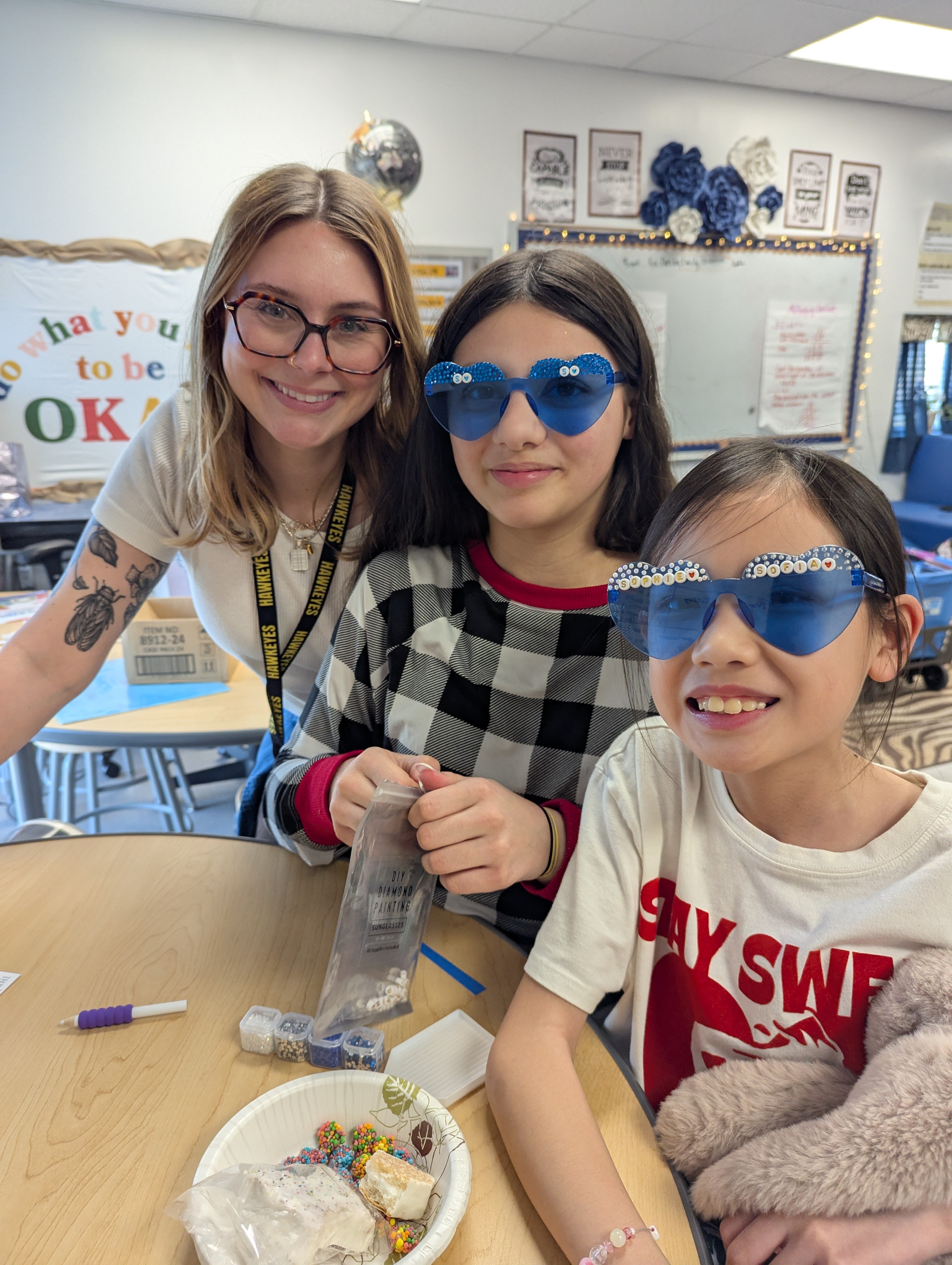 Teacher and two students proudly showing off personalized heart-shaped jeweled sunglasses and kits