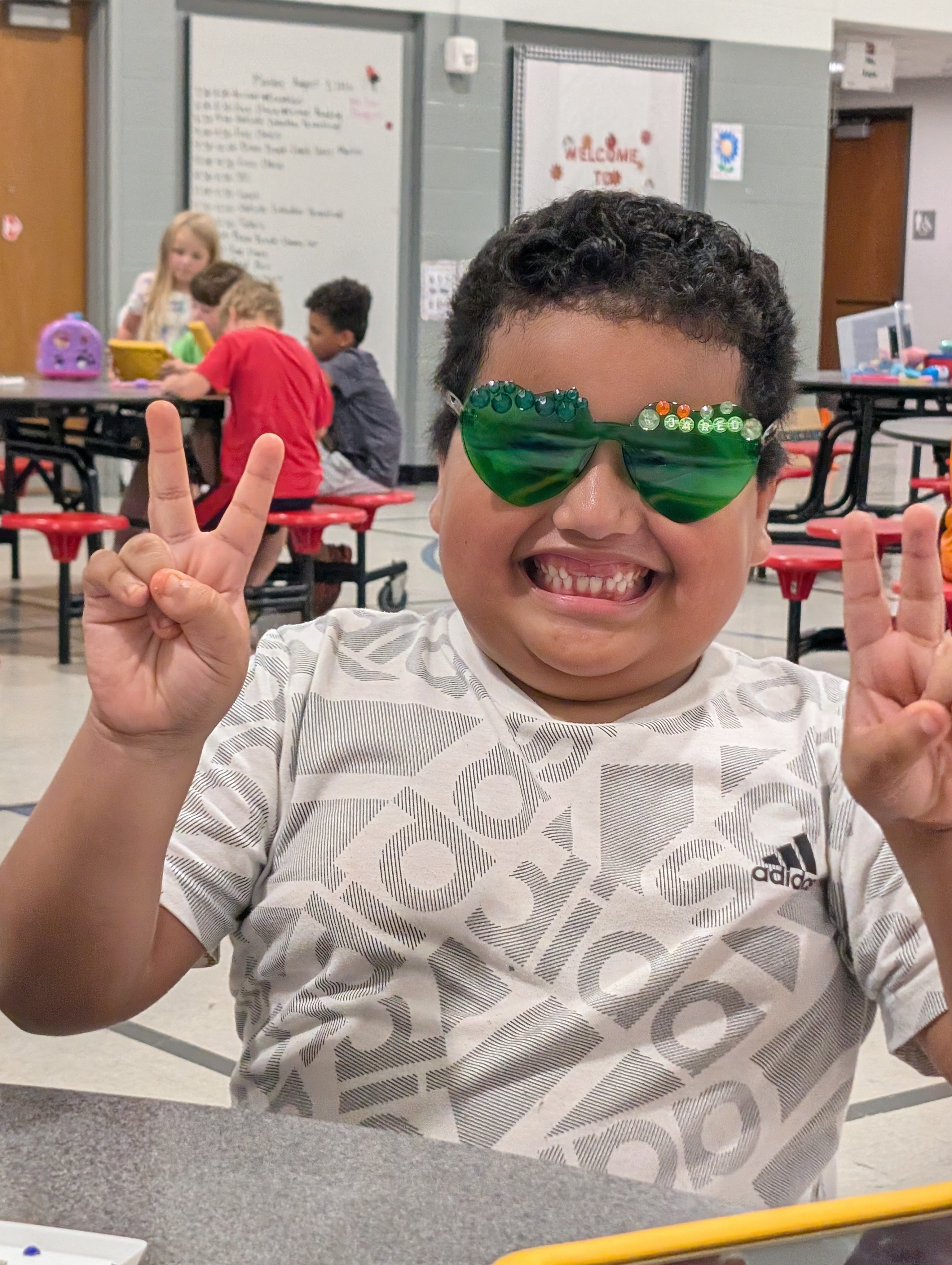 Happy boy wearing green jeweled diamond art sunglasses giving peace signs