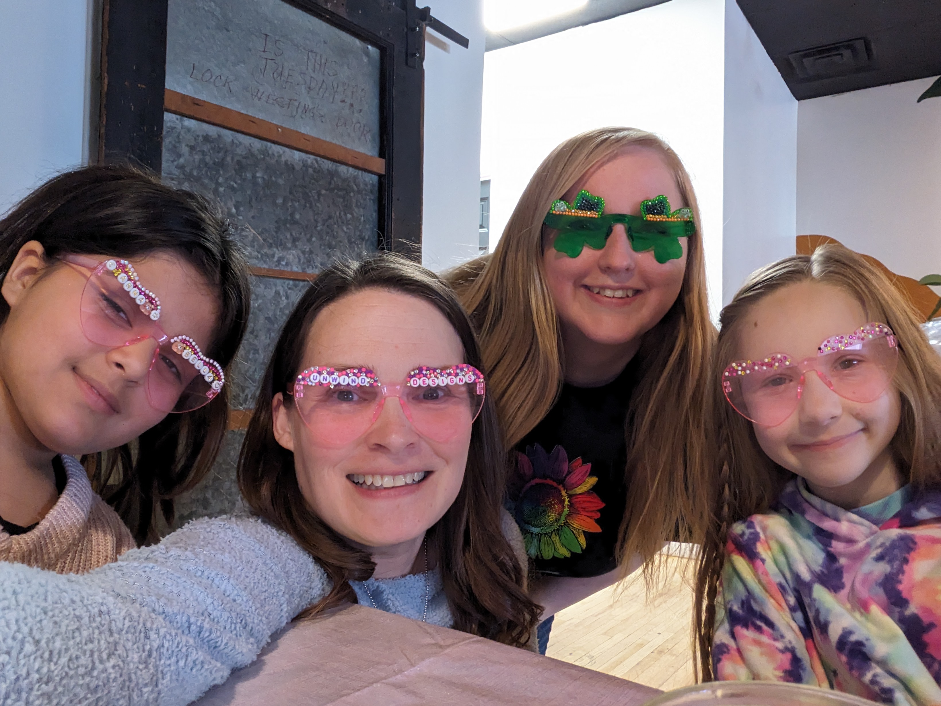 Mom and daughters smiling together wearing custom jeweled heart and shamrock sunglasses