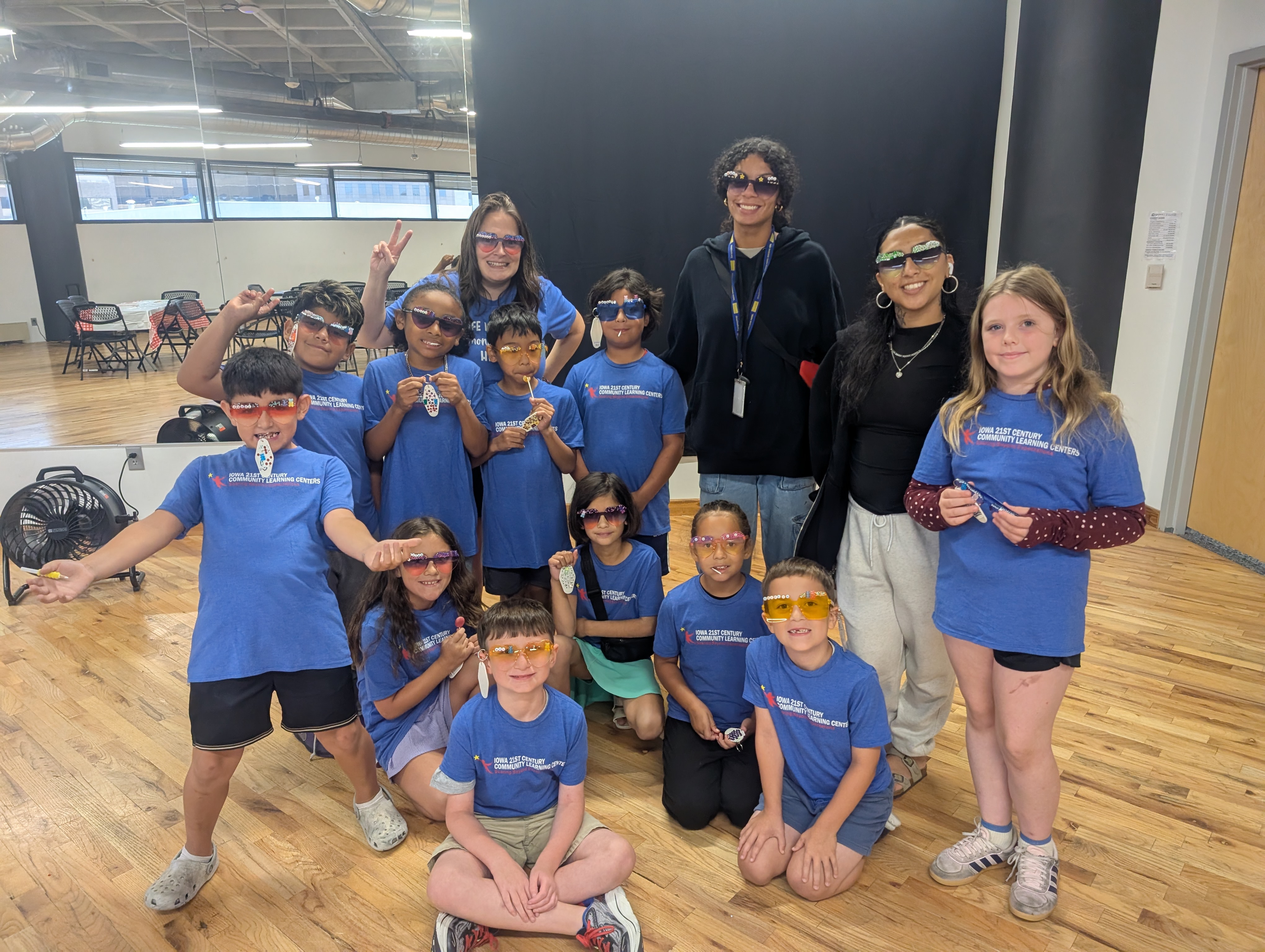 Group of students and instructors in blue learning center shirts proudly modeling jeweled sunglasses