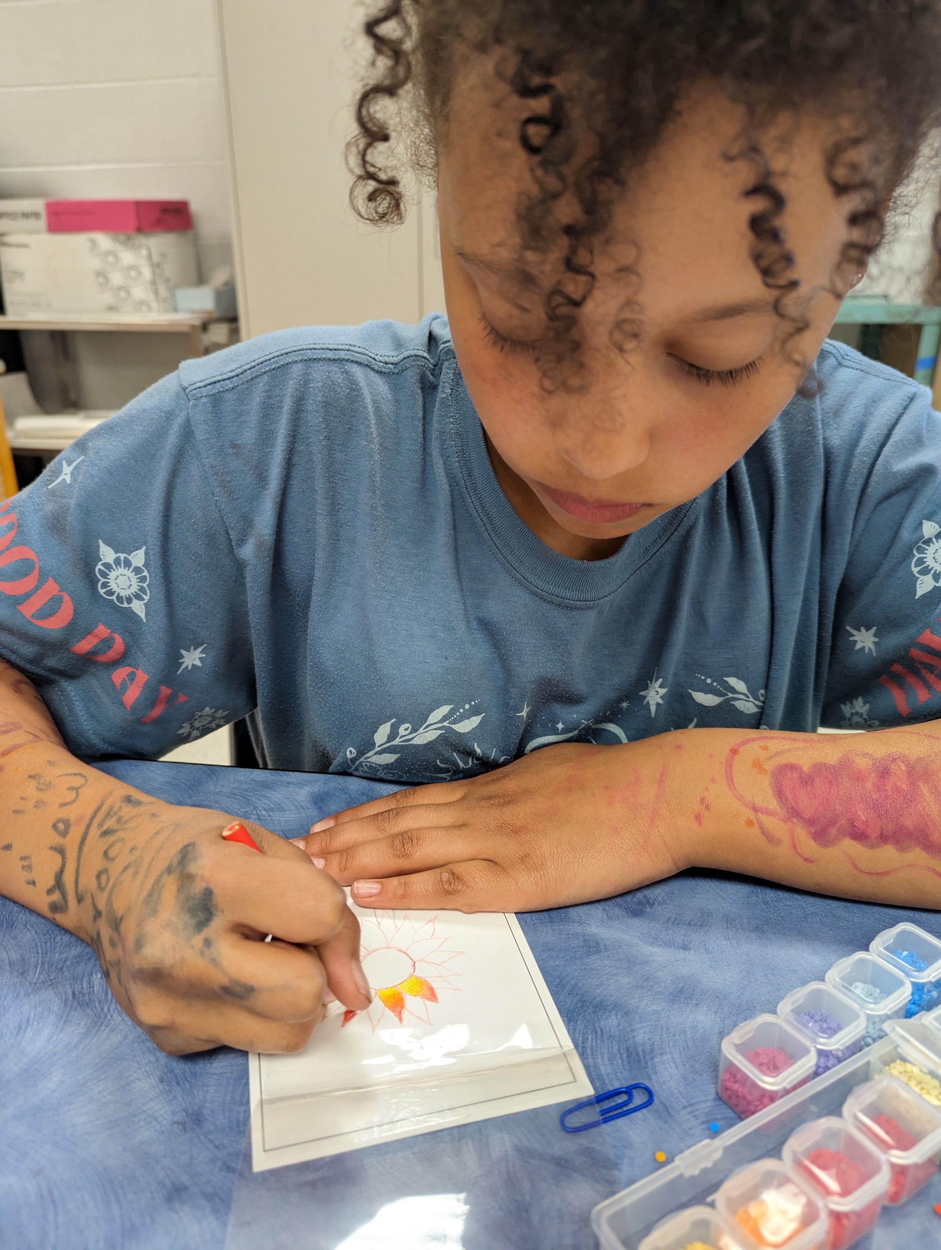 Young girl coloring and diamond painting a warm sunflower design with gem organizer