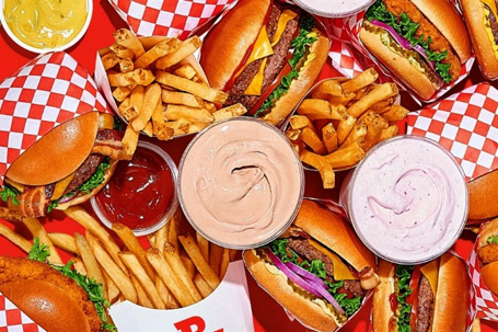A delicious overhead spread of burgers, fries, chicken sandwiches, milkshakes, and dipping sauces