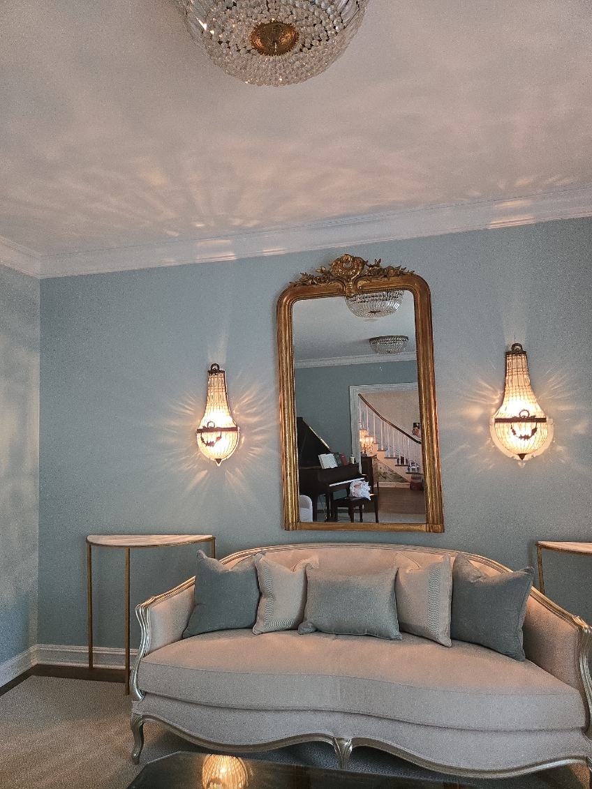 Crystal wall sconces on either side of a gold mirror