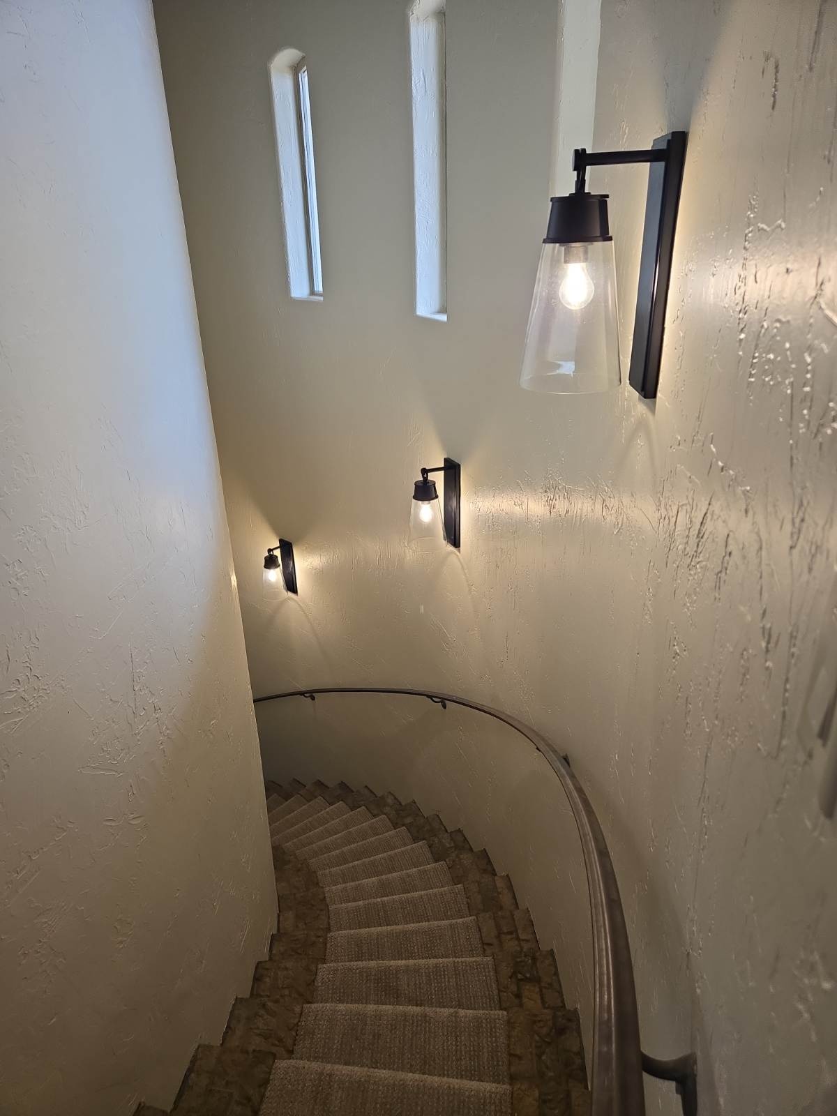 Wall sconces lighting a curved staircase