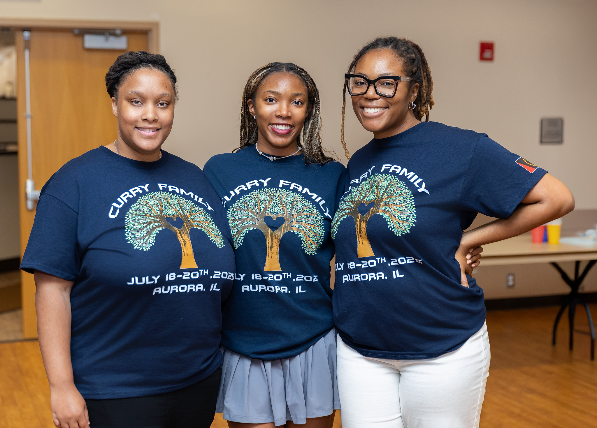 Three young Curry family members smiling together in reunion shirts