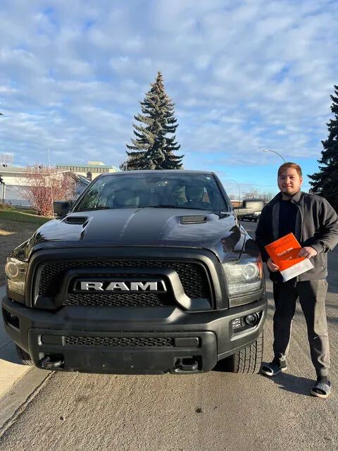 Smiling customer beside new black RAM pickup truck