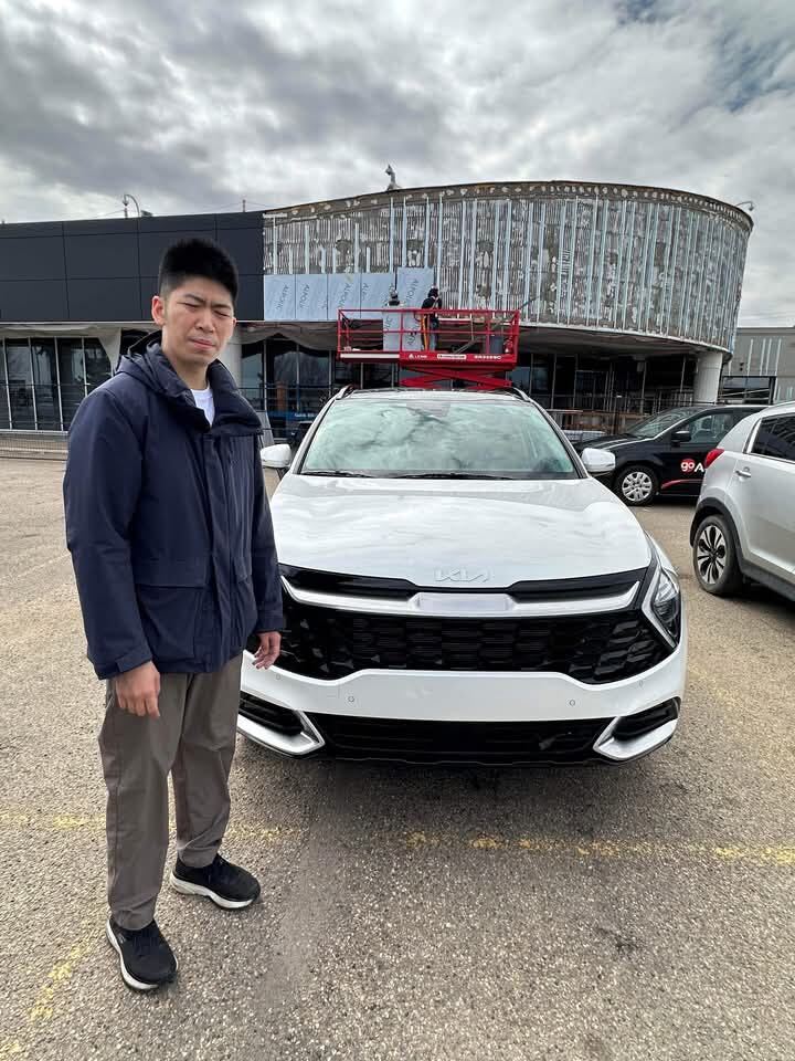 Happy customer standing with new white Kia SUV