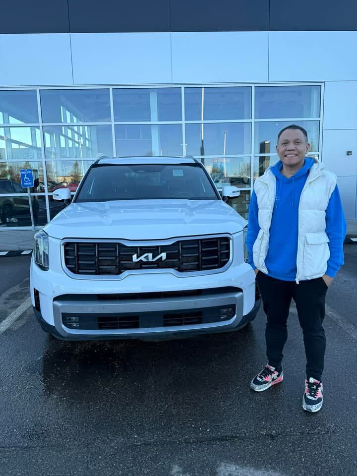Smiling customer standing with new white Kia SUV