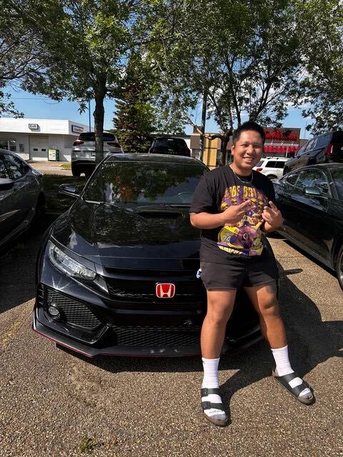 Smiling customer flashing peace signs in front of black Honda Civic