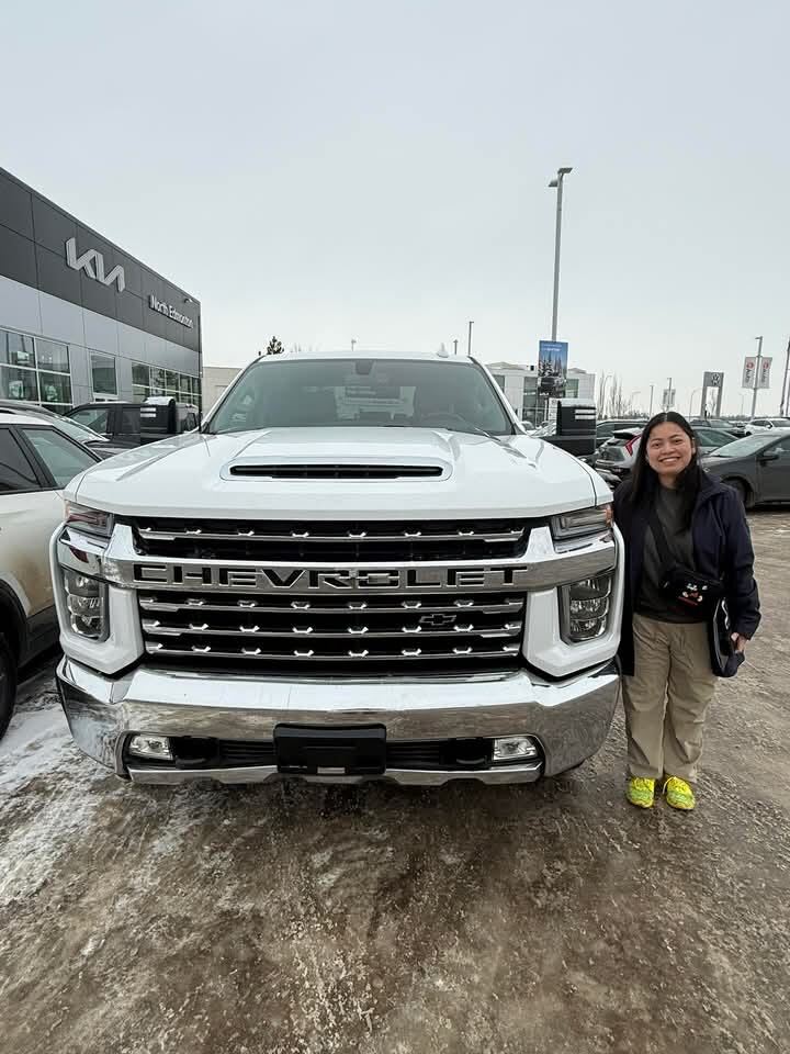 Client smiling next to new white Chevrolet pickup truck