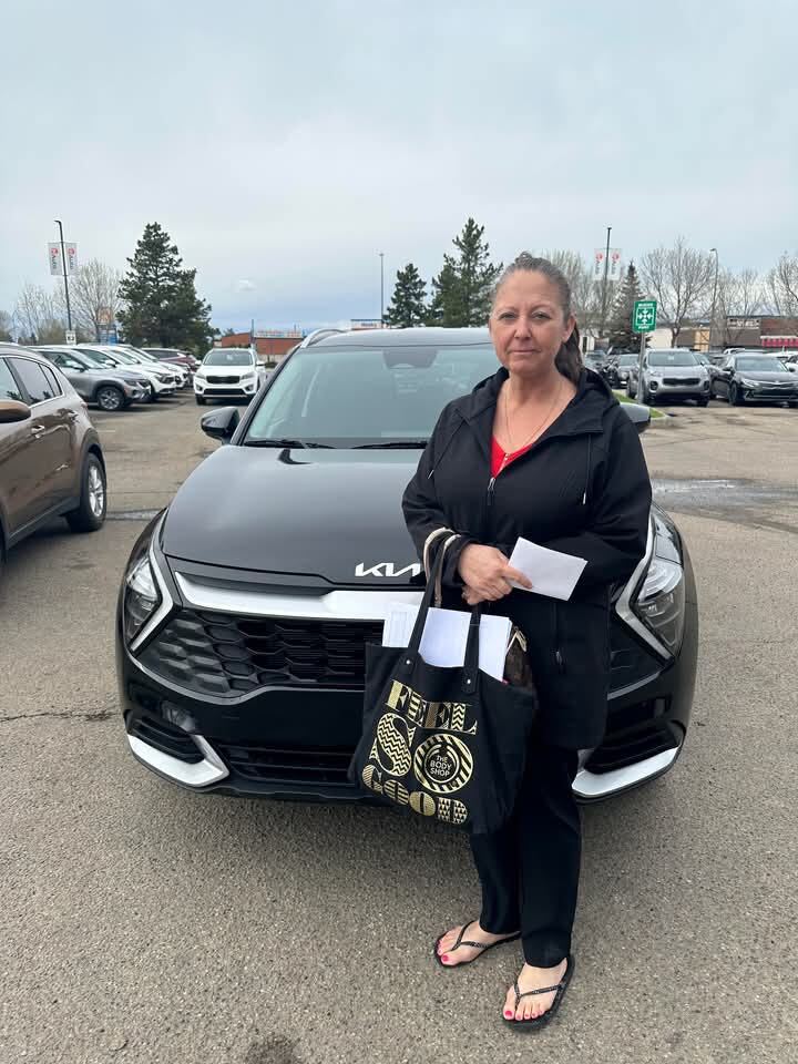 Customer standing in front of new black Kia SUV