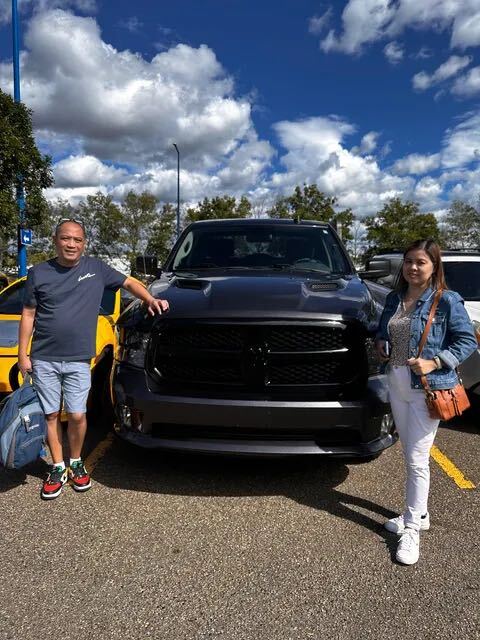 Couple smiling beside their dark grey pickup truck