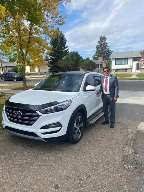 Client in suit standing beside white Hyundai SUV