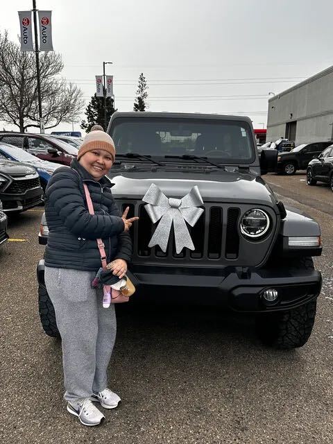 Happy customer beside dark grey Jeep with big silver bow