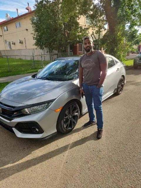 Smiling client standing beside silver Honda sedan