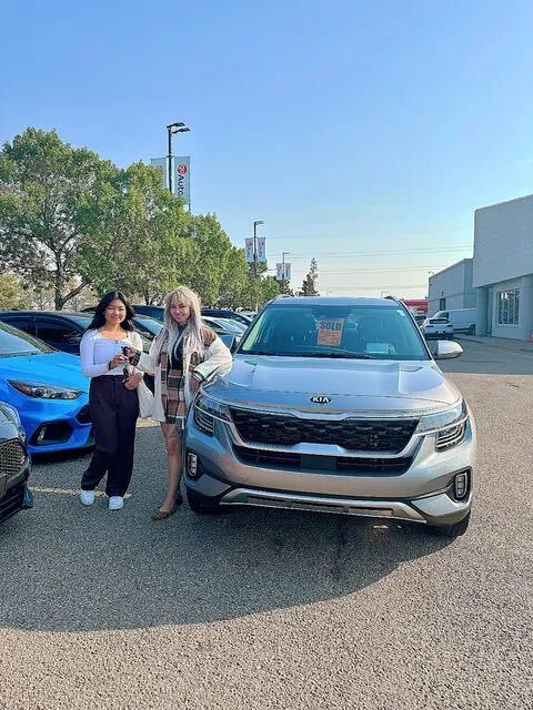 Two happy buyers with silver SUV