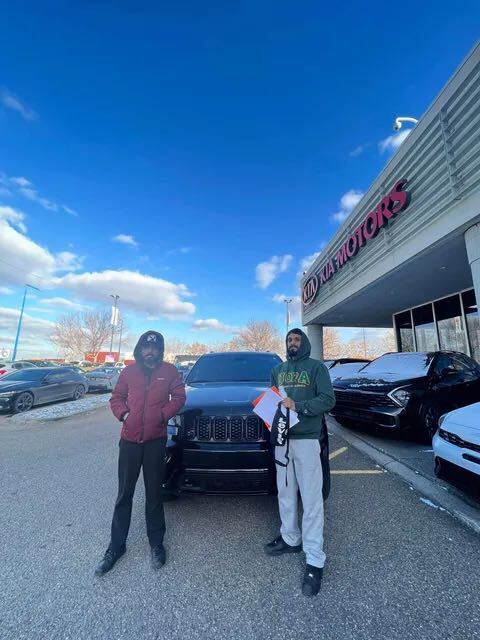 Two clients with black SUV at dealership