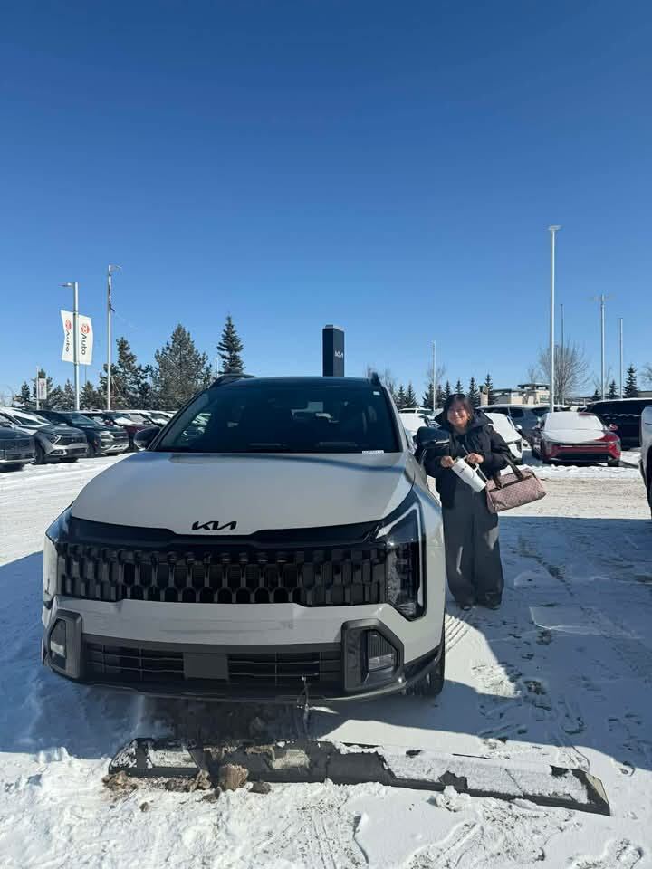 Client smiling beside grey Kia SUV in winter
